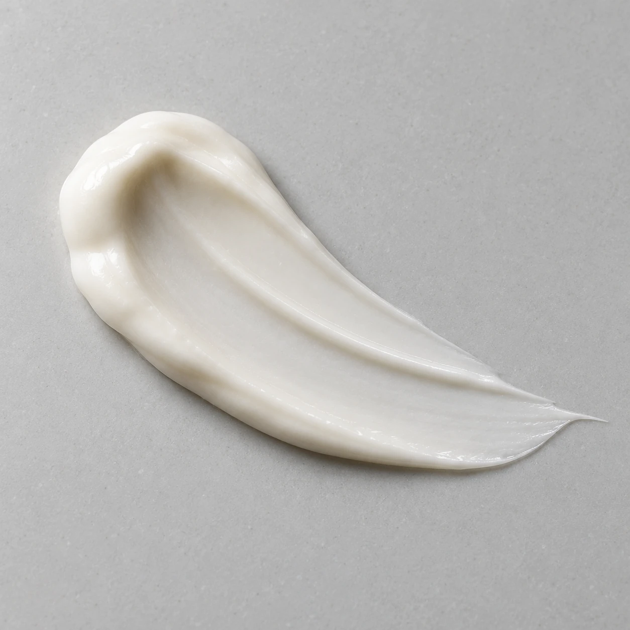Opaque ivory cream swipe with a raised edge and a taper on a neutral surface