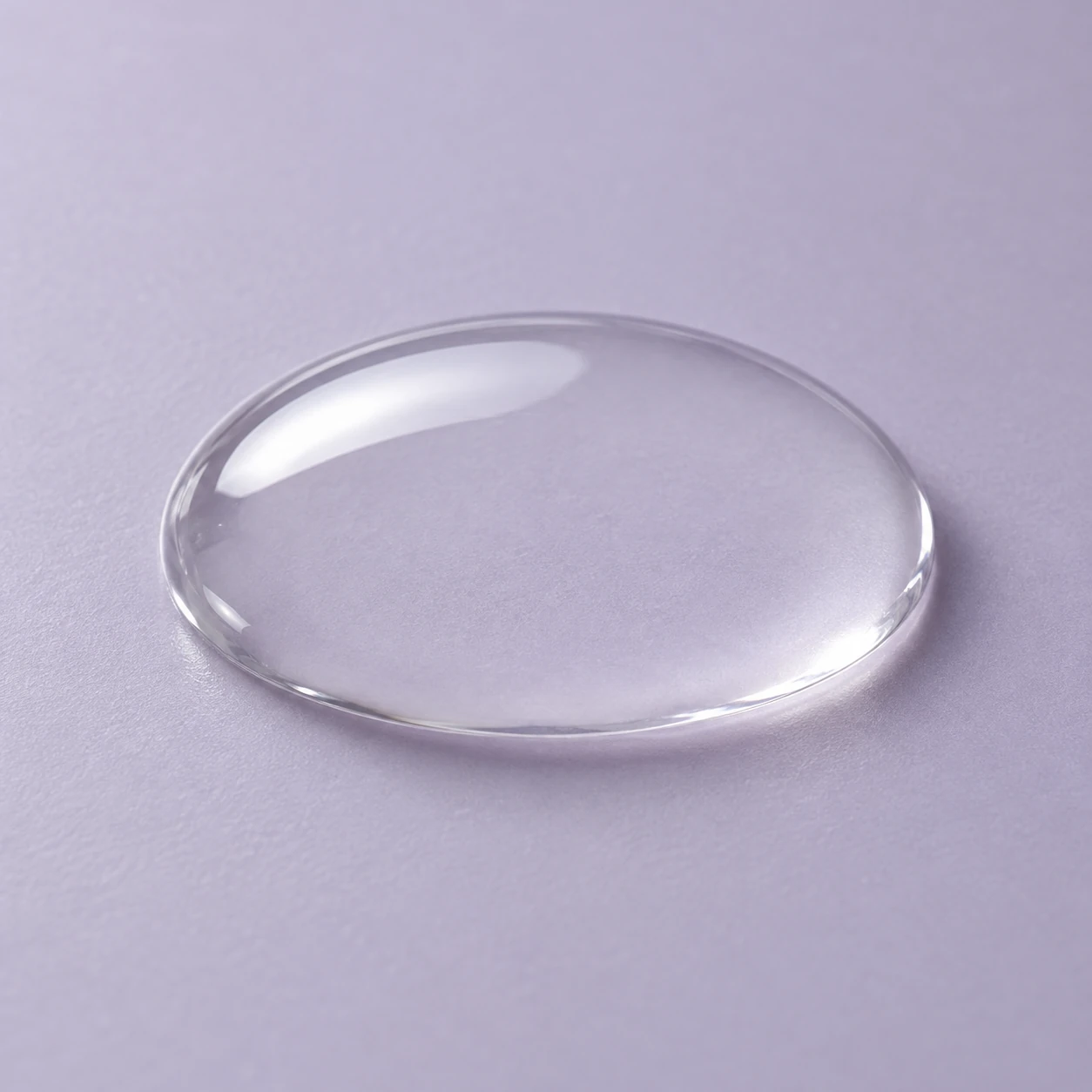 Single clear serum droplet resting on a plain surface with controlled highlights