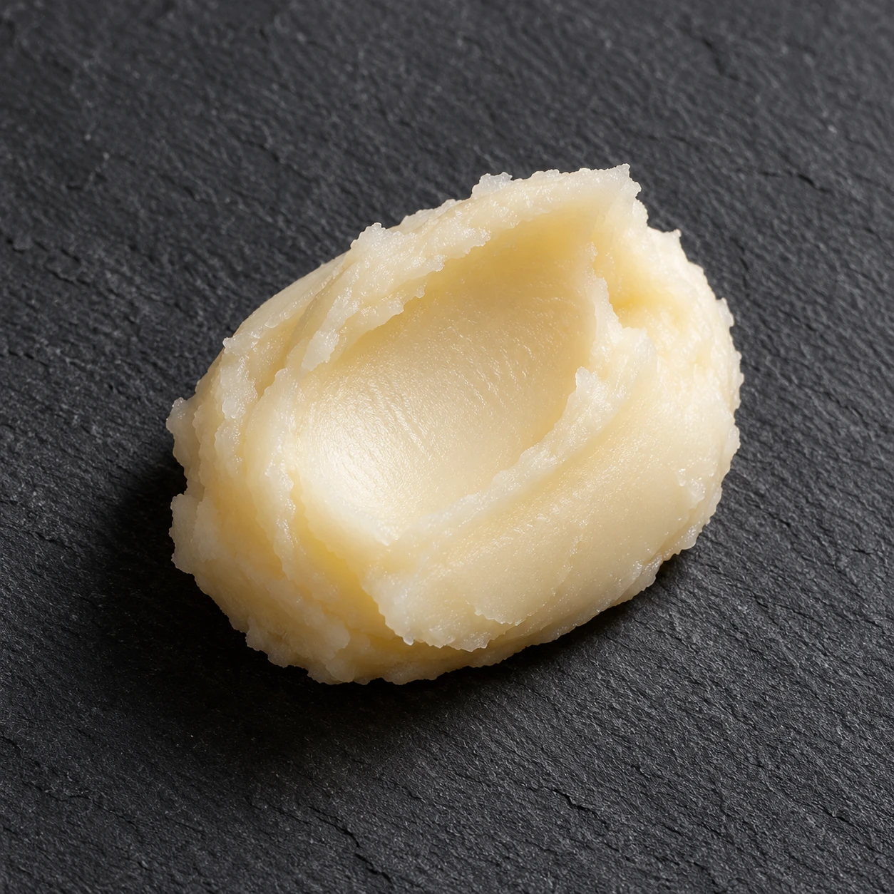 Single pale balm scoop with shallow tool marks and a cohesive supported edge