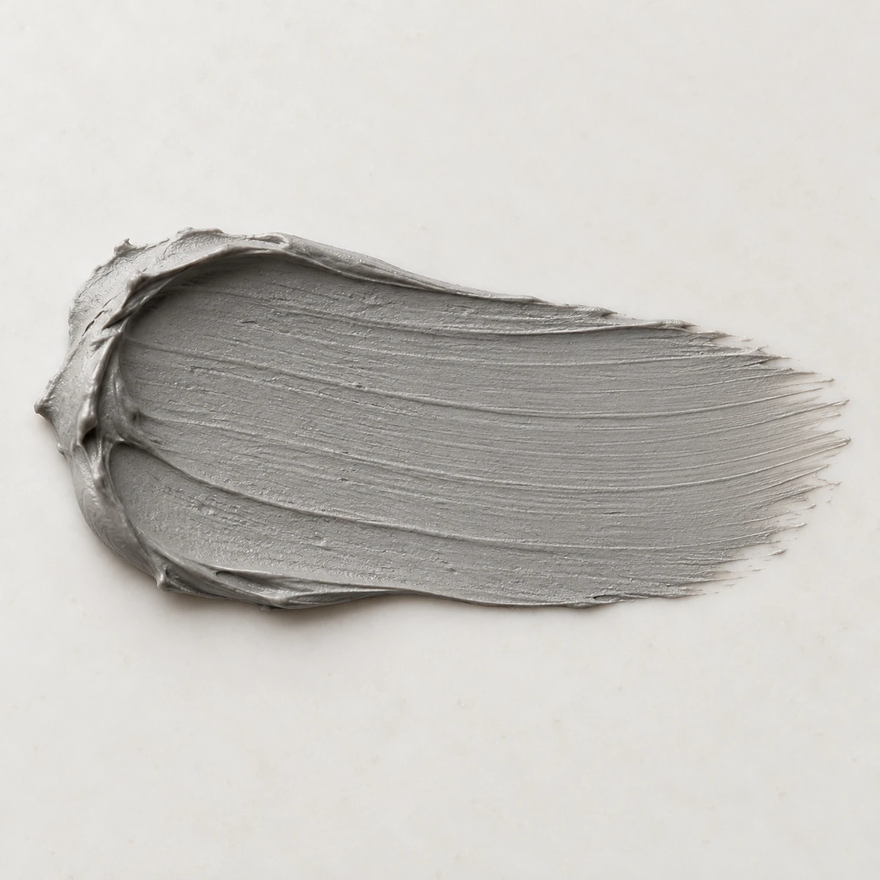 Matte clay-mask swatch with subtle spreading marks on a neutral support